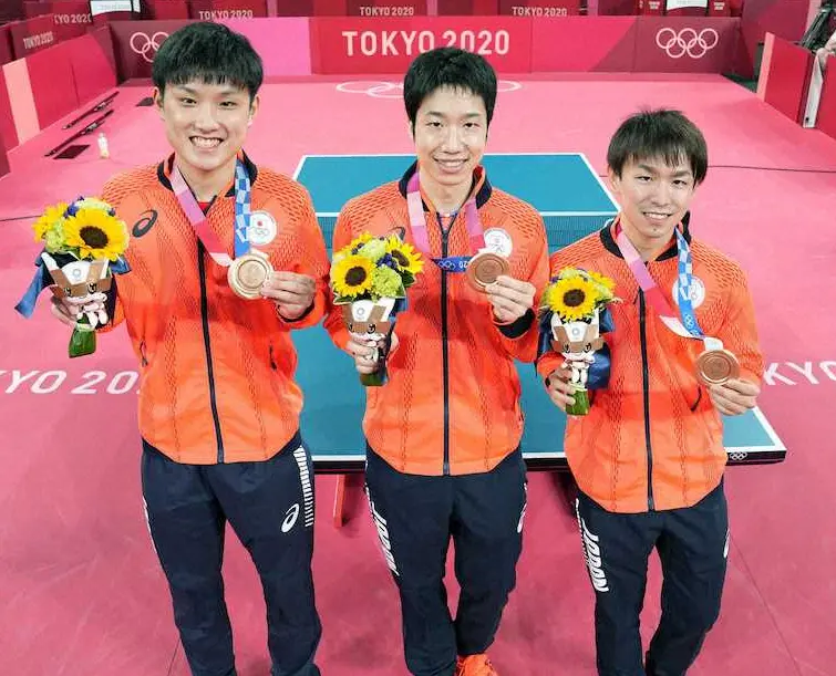 男子団体で獲得した銅メダルを手に、笑顔で記念写真に納まる（左から）張本智和、水谷隼、丹羽孝希