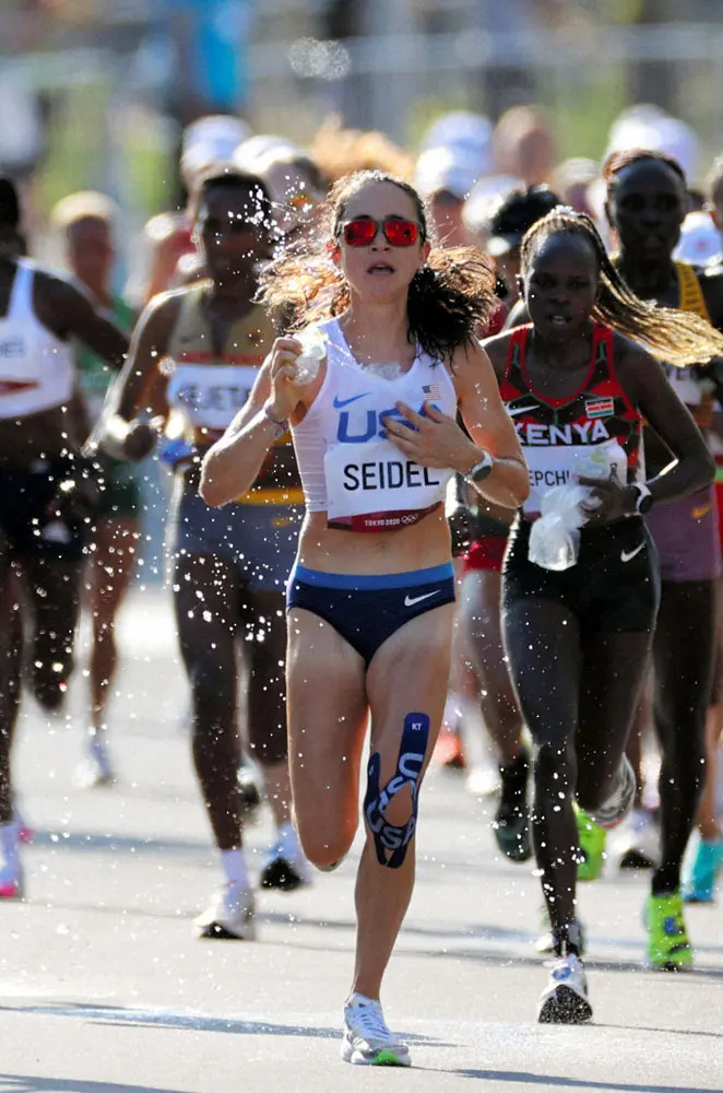レース中に氷を胸元に入れ、体に水をかけてクールダウンする女子マラソンの選手