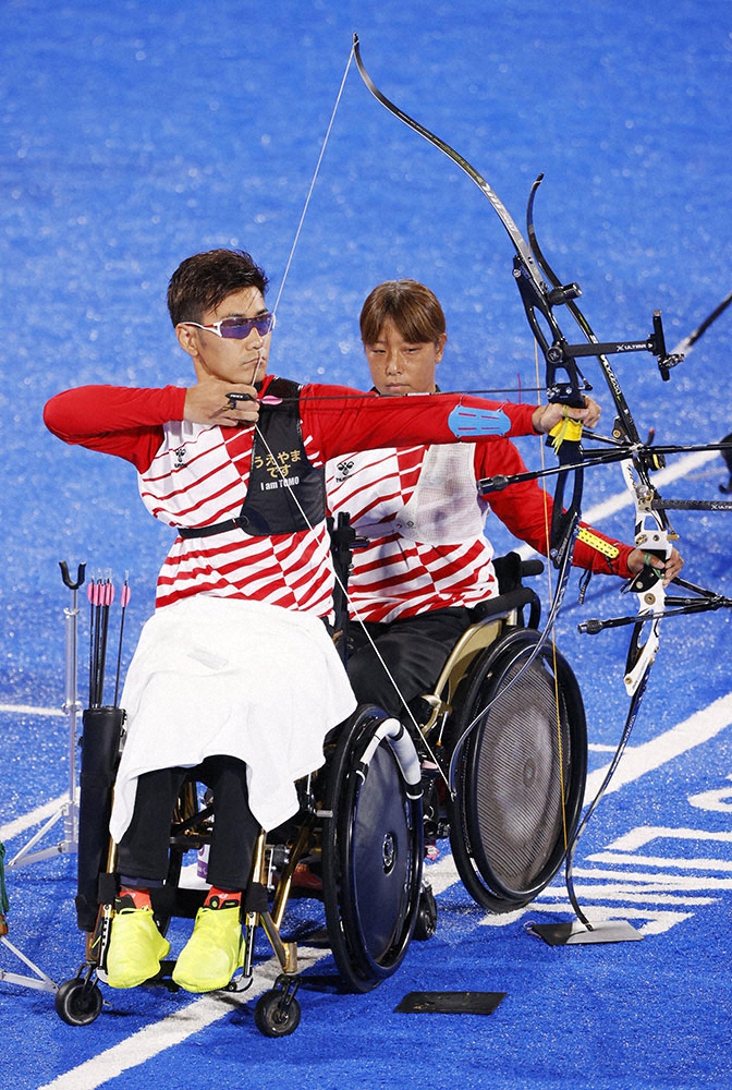 東京パラリンピック、アーチェリーの混合リカーブ団体（車いす、立位など）準々決勝で、的を狙う上山友裕（手前）。右は重定知佳