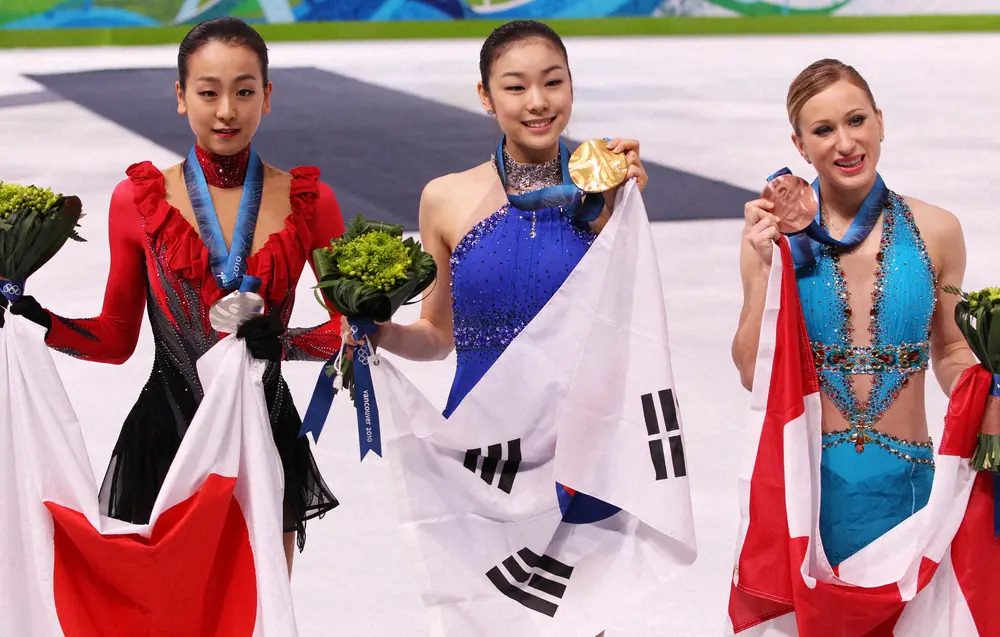 ＜2010年バンクーバー五輪　フィギュア女子フリー＞表彰台でメダルを手に笑顔を見せる（左から）銀メダルの浅田真央、金メダルのキム・ヨナ、銅メダルのジョアニー・ロシェット（カナダ）