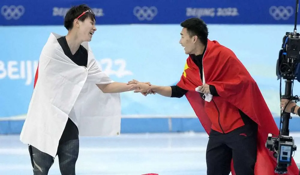 スピードスケート男子500メートルで銅メダルを獲得し、金の高亭宇（右）と握手を交わす森重航（共同）