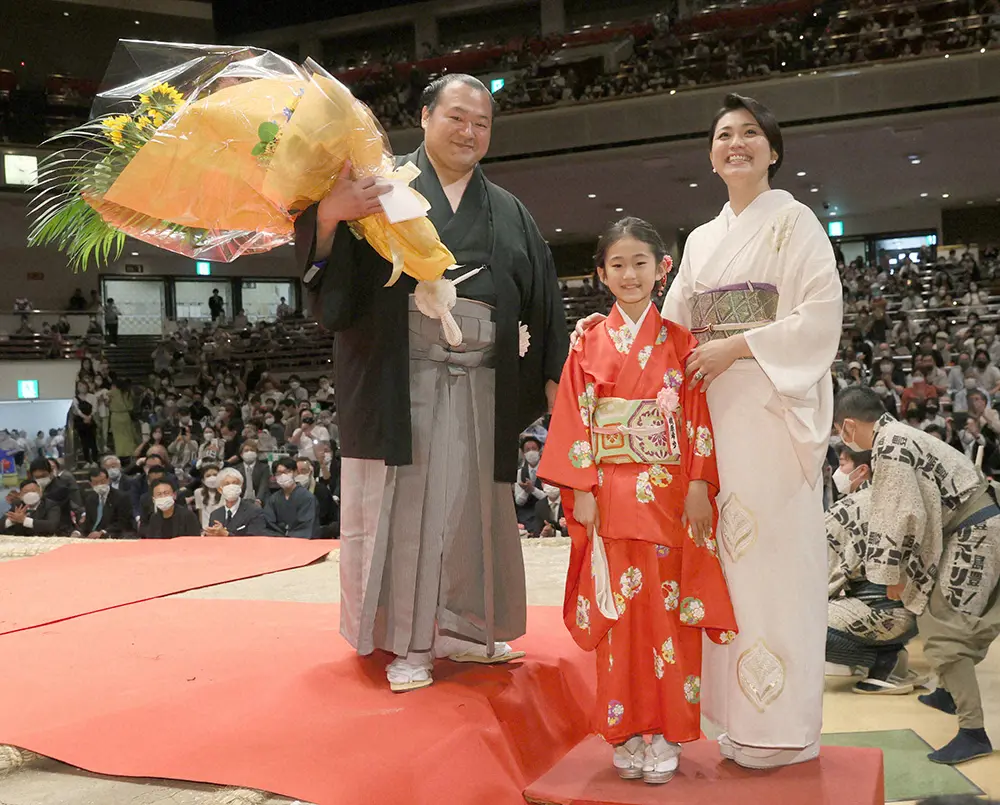 家族から贈られた花束を手に笑顔を見せる元豊ノ島の井筒親方。右から妻・沙帆さん、長女・希歩さん（代表撮影）